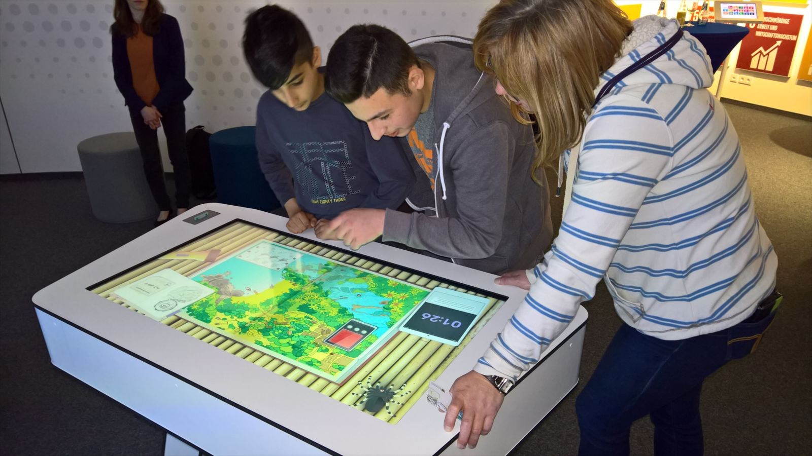 Jugendliche spielen gemeinsam an einem großen Multitouch-Tisch