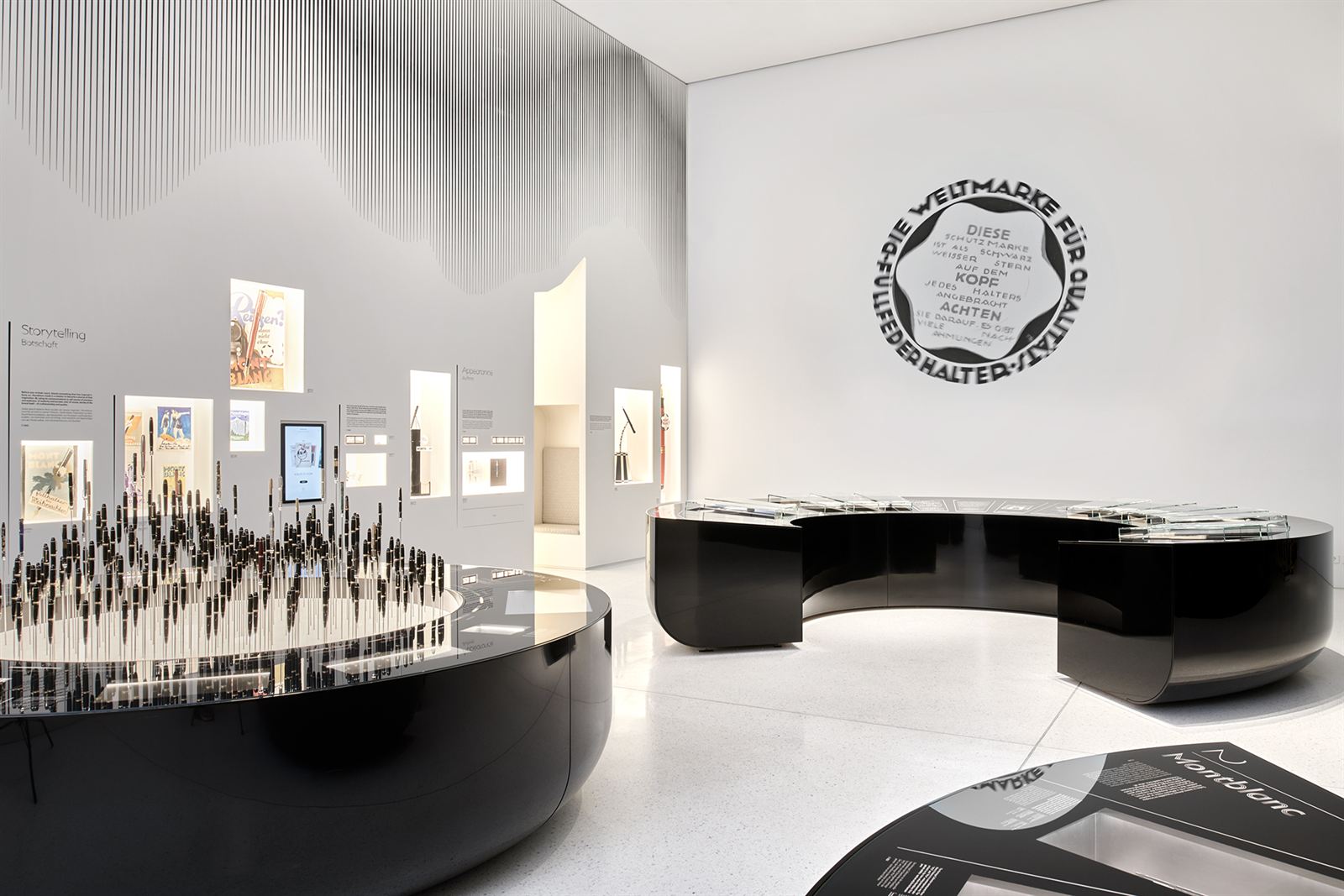 Heller Ausstellungsraum mit runden schwarzen Vitrinen voller Füllfederhalter
