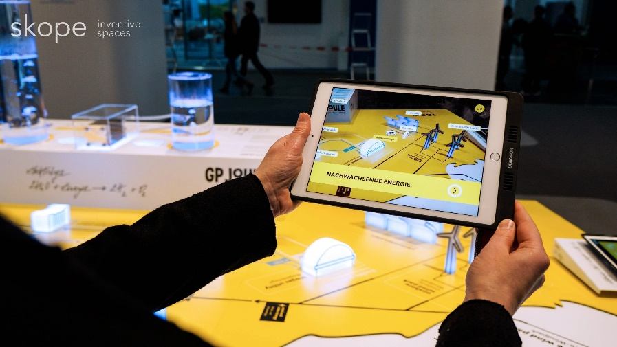 Tablet mit Augmented-Reality-Ansicht über dem Messemodell von GP Joule