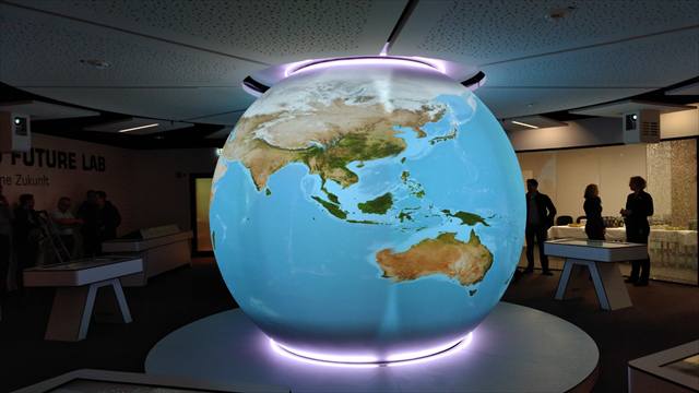 Beleuchteter Globus im Zentrum der Ausstellung, umgeben von Spielstationen