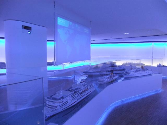 Kreuzfahrtschiffmodelle in blau beleuchteter Vitrine mit Projektionsfläche
