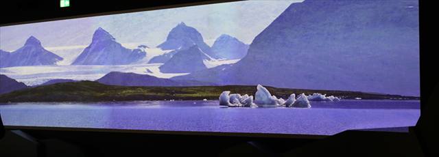 Breite Projektion einer arktischen Berglandschaft mit Eisschollen im abgedunkelten Raum