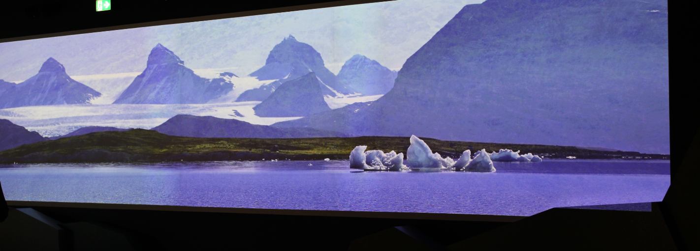Breite Projektion einer arktischen Berglandschaft mit Eisschollen im abgedunkelten Raum