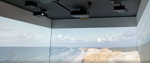 Mehrkanalige Projektion einer Küstenlandschaft über drei aneinandergrenzende Wände, Projektoren an der Decke