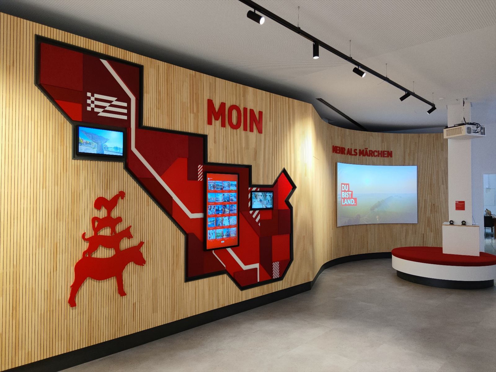 Holzwand mit roten Grafiken, Bildschirmen und Stadtmusikanten-Silhouette, im Hintergrund ein Curved Screen